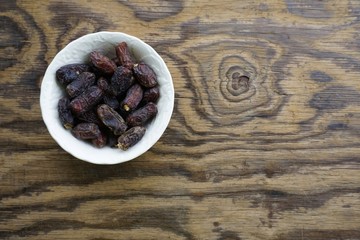 Bowl of dried dates on texture wooden background