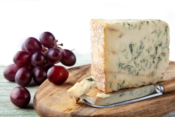 Stilton on a cheese board with red grapes and cheese knife