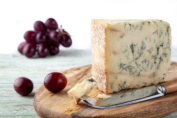 Stilton on a cheese board with red grapes and cheese knife