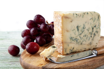 Stilton on a cheese board with red grapes and cheese knife