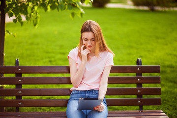 Pensive girl with tablet sitting on the bench