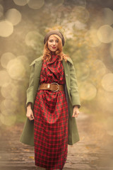 Young redhead girl in hat and coat at outdoor. Rainy day in autumn season