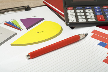 Charts, calculator and pen on wooden office table. Financial and business concept.