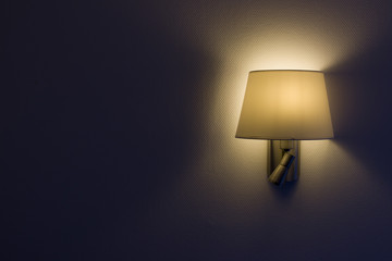 Wall lamp, night light in a dark background, yellow shade.