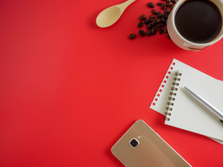 Top view,flat lay red desk with coffee,notebook and smart phone with copy space
