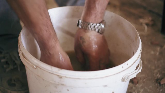 A man is washing hands ina dirty water from the bucket after finishing work