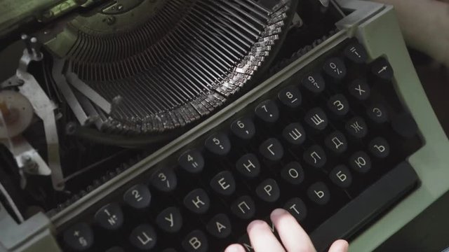 Little six-year-old boy studies the work of an old typewriter. Close-up hands