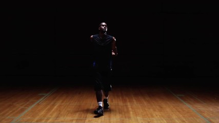 A basketball player receives a pass and takes a jump shot on a dark court