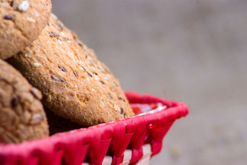 homemade oat cookies with sunflower seeds in and near checkered basket on burlap background