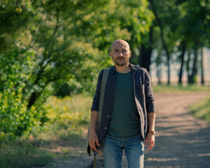Naklejka na ściany i meble bald bearded man walks through the park.