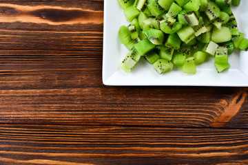 Freshly sliced kiwi fruit with whole kiwis in background.