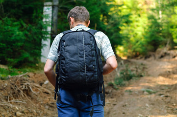 man with black backpack traveling in the mountains, travel concept in the wild, copy space, closeup,