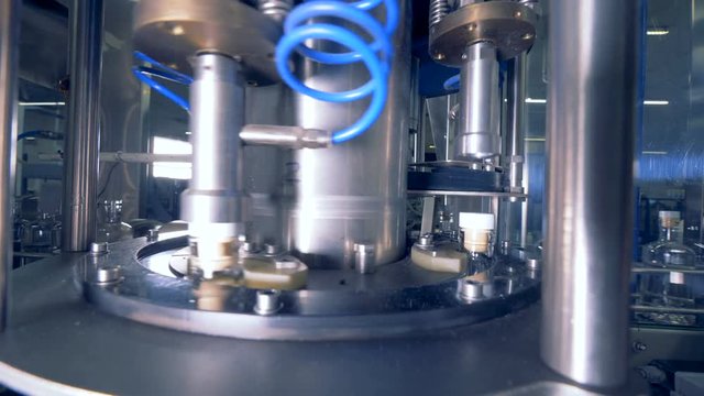 A machine puts caps on bottles. 