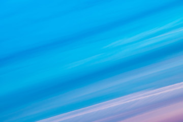 Varicolored striped surreal sky with shades of blue, cyan, cobalt, pink, purple, magenta colors. Diagonal lines of smooth clouds. Atmospheric background image of tender sky.