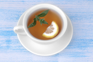 A cup of tea with mint and lemon on a blue wooden background