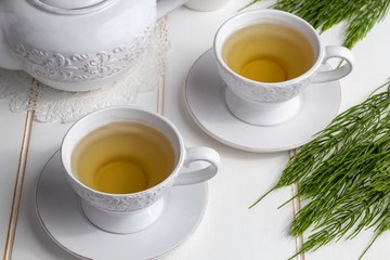 Two cups of horsetail tea with fresh Equisetum arvense twigs