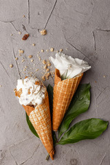 A creamy ice cream with granola and white flowers on a concrete table. View from above.