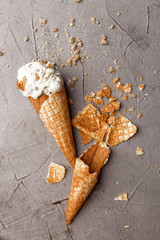 A creamy ice cream with granola and white flowers on a concrete table. View from above.