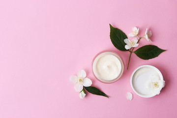 a jar of cosmetic cream with flowers on a colored background.minimalism, top.