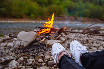 person resting near riverside with camp fire. hiking concept