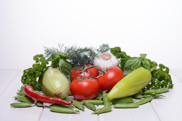 Various fresh vegetables are on a wooden table and on a white background
