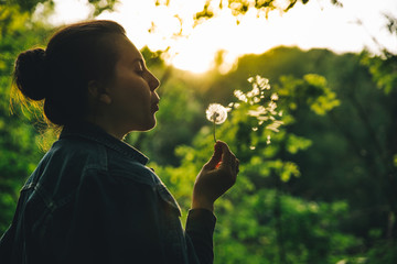 woman blowing dandelion on sunset. copy space