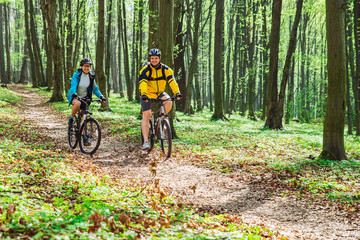 Naklejka premium couple riding bicycle in forest in warm day