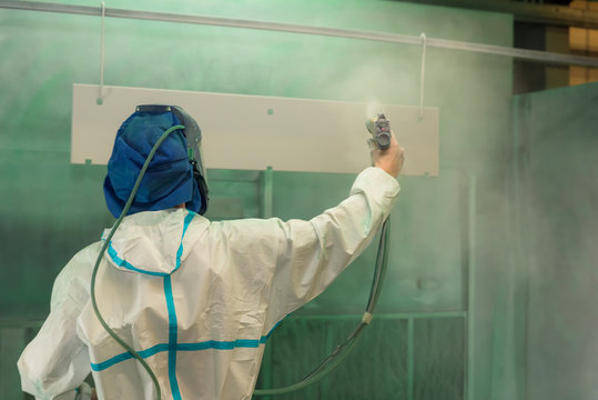 Man Spray Painting In Protective Clothing