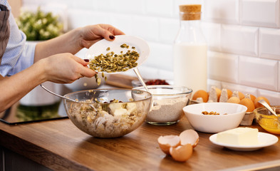 women's hands prepare dough with nuts and seeds for cookies