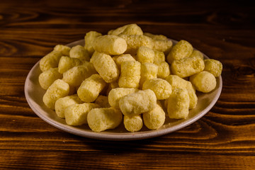 Ceramic plate with corn sticks on wooden table