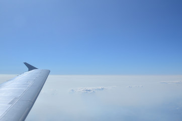 Fototapeta premium Part of an airplane wing, cloudscape and blue sky