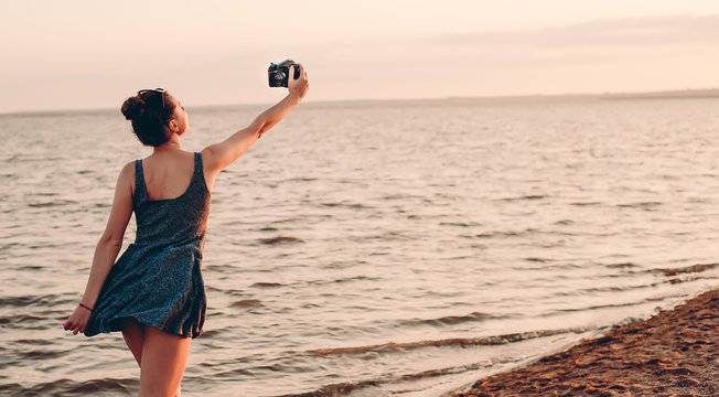 beautiful girl at sunset by the sea, takes pictures of herself on the photoport, bright emotions