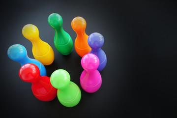 Colorful bowling pins or skittles on dark background, top view
