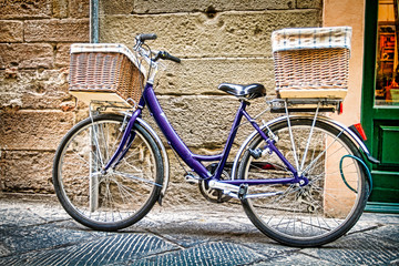 Fototapeta na wymiar Blue bicycle with woven baskets leans against a stone wall