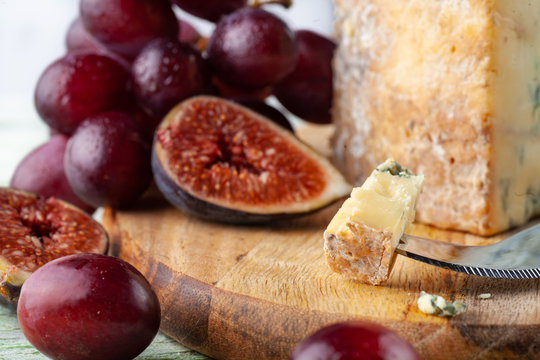Stilton on a cheese board with red grapes, fig and cheese knife