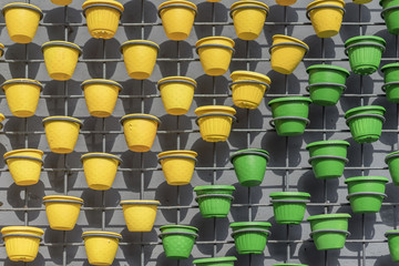 Fototapeta premium Wall art decor from grid with bright green and yellow flower pots on concrete wall. Modern city background, texture