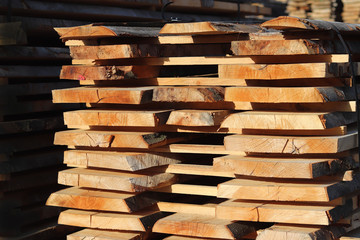 Large wooden planks stacked in racks for drying under the open sky in an industrial area. Timing of...