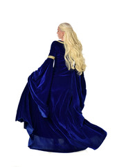 full length portrait of pretty blonde lady wearing  a blue fantasy medieval gown. standing pose on white background.