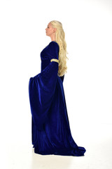 full length portrait of pretty blonde lady wearing  a blue fantasy medieval gown. standing pose on white background.