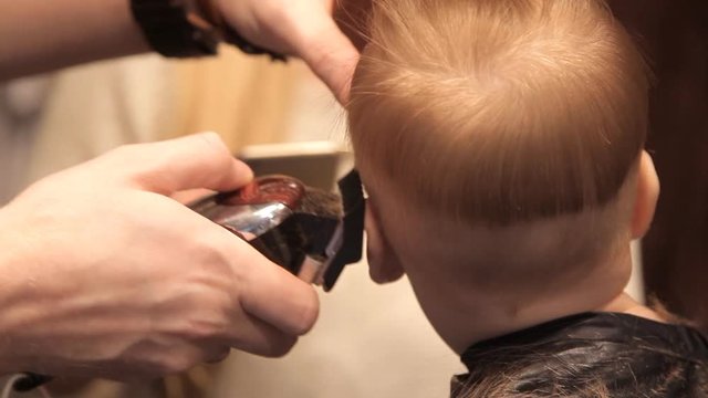 In a brutal hairdresser's, a young child is being sheared by a clipper