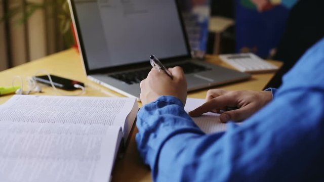 business man left hand holding pen writing report copywrite using laptop notebook typing text on keyboard closeup desk top blue shirt modern technology developer busy lifestyle enjoying self-education