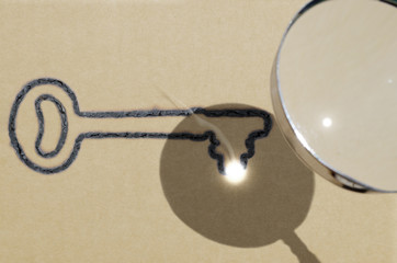 Focus is key (one key version), illustrated by using magnifying glass to focus sunlight to create key shaped burn mark on piece of brown paper