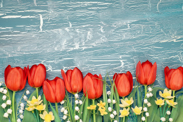 Bunch of red tulips, daffodils and lily of the valley flowers on rustic background