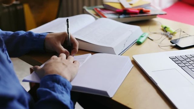 close-up view of male hand using pen writing text in diary with opened book and modern technology on background modern urban comfortable lifestyle working hard studying process left handed man
