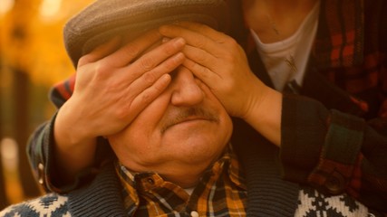 Old man are surprised with his eyes closed by the hands