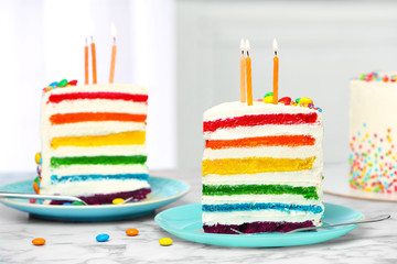 Delicious rainbow cake with candles for party on table