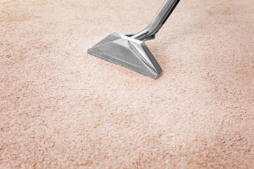 Removing dirt from carpet with professional vacuum cleaner indoors