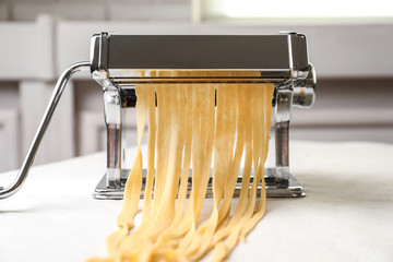 Pasta maker with wheat dough on table