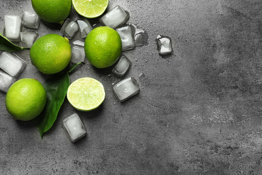 Composition with fresh ripe limes and ice cubes on gray background, top view