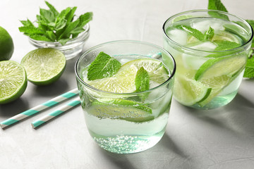 Refreshing beverage with mint and lime in glasses on table